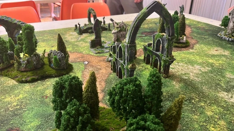 Arches gothiques en ruine couvertes de lierre au milieu d'une forêt de wargame
